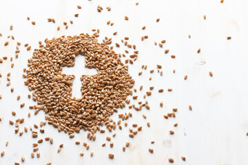 mound of wheat berry grain with cross shape in middle on white wood with copy space