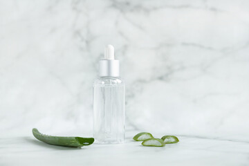 natural herbal cosmetic product, gel with aloe vera extract for skin care. healing moisturizing serum on marble background. revitalizing liquid with drop on pipette. beauty concept. soft focus