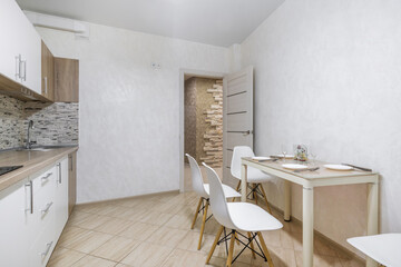 Fototapeta na wymiar Interior of the modern luxure kitchen in studio apartments in minimalistic style with light white color