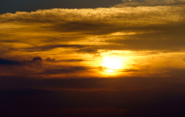 Naklejka na ściany i meble beautiful sunset sky, bright sun and dark silhouette of clouds as a background