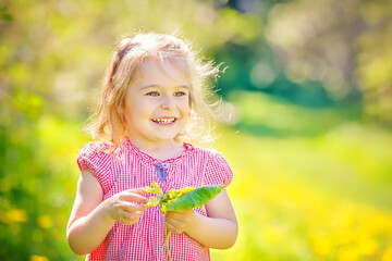 Happy little girl playing with bouquet in sunny park