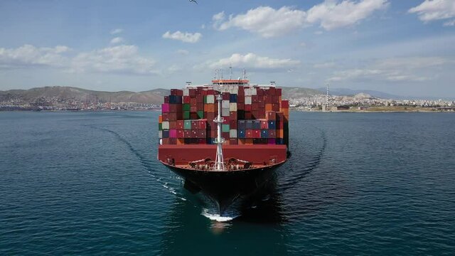 Aerial drone video of huge container carrier tanker ship front bow cruising deep blue open ocean sea