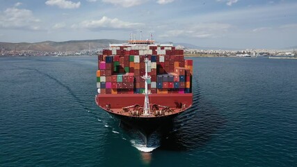 Aerial drone video of huge container carrier tanker ship front bow cruising deep blue open ocean sea
