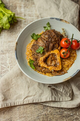 Osso buco traditional italian meat dish served with herbs and tomatoes