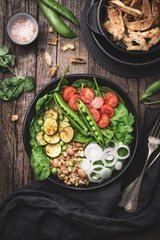 Healthy dinner, lunch. Vegetarian Buddha bowl or healthy salad with balanced ingredients. Spinach, grilled zucchini, grains, beans, green onions, cherry tomatoes and fresh peas served with croutons 