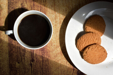 Cup of coffee and a dish with crackers on the table. Spanish breakfast. Table illuminated by a sunrise. Food  raised