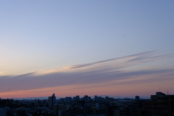 兵庫県神戸市東灘区の高層マンションの上層階からの夜明け。大阪生駒山から太陽が昇り、あたりはオレンジ色に染まり、ビル群がシルエットで浮かぶ。