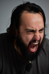 portrait of young man screaming. Man with long hair and long black beard yelling, angry. Mad with the life and frustrated.