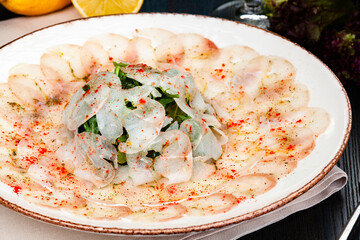 Dorado fish carpaccio served with arugula salad on white plate.
