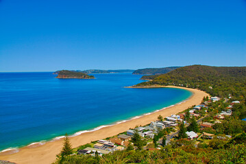 Fototapeta na wymiar Beautiful Pearl Beach And Broken Bay are seen from the view at Mount Ettalong lookout above the New South Wale's coastal town of Pearl Beach in Australia.