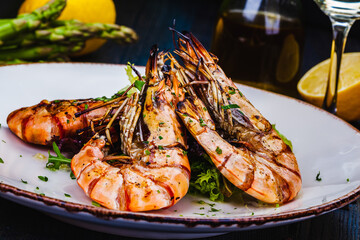 Grilled tiger prawns with greens on white plate