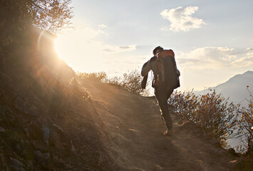 Joven subiendo una montaña con mochila en un hermoso atardecer. Campamento en la montaña