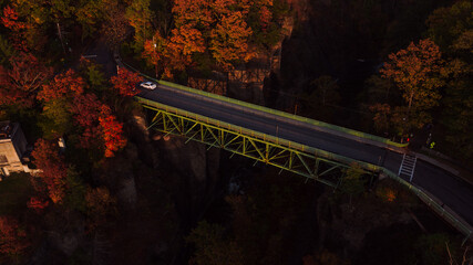 Aerial of Stewart Avenue Deck Truss Bridge over Canyon & Waterfall - Peak Autumn Colors - Ithaca, New York