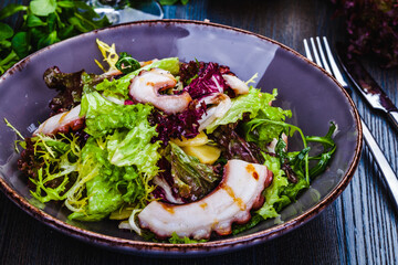 Octopus salad with potatoes and mixed greens on a plate
