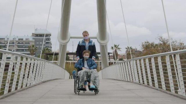 Mother walking with son in wheelchair