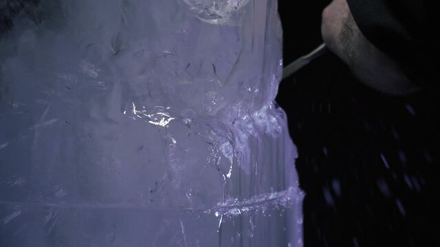 Artist is working with a chisel in the studio shaping an ice sculpture, 4k