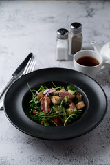 Bacon and rocket spicy salad with roasted croutons on a stone table in a restaurant