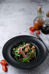 Bacon and rocket spicy salad with roasted croutons on a stone table in a restaurant
