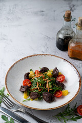 Menu photography setting: roasted liver salad, a glass of wine and open book, side view, soft light
