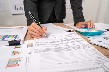 Businesswoman signing contract document with pen on a desk at office