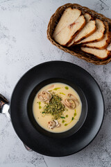 Above shot of a cream cheese soup with fettuccine nests in a black bowl, grey stone background, menu photography