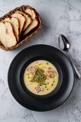 Above shot of a cream cheese soup with fettuccine nests in a black bowl, grey stone background, menu photography