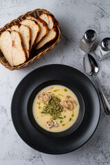 Above shot of a cream cheese soup with fettuccine nests in a black bowl, grey stone background, menu photography