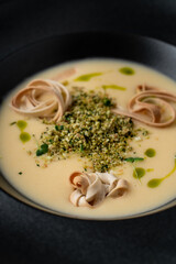 Cream cheese soup with pasta inside, close up in a black bowl