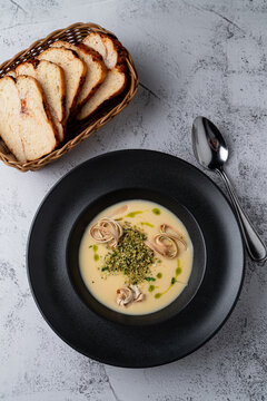 Above shot of a cream cheese soup with fettuccine nests in a black bowl, grey stone background, menu photography