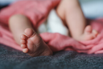 Close up on feet of unknown baby lying on the bed newborn concept