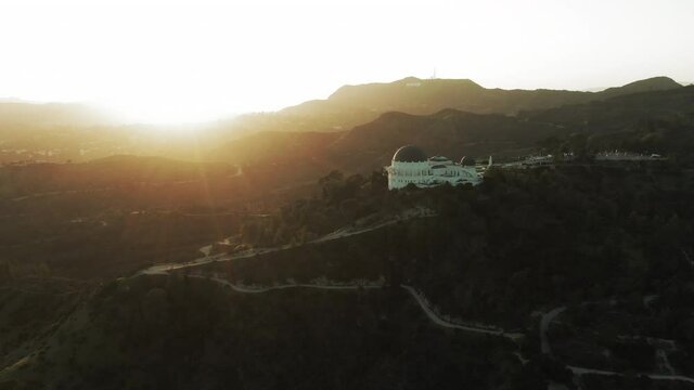 Aerial Panning Shot Of Famous Observatory On Mountain Against Sky, Drone Flying Over Landmark At Sunset - Los Angeles, California