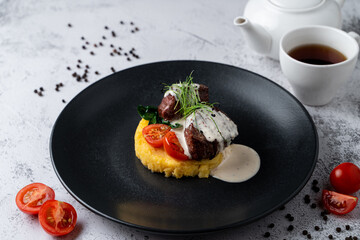 Filet mignon with mashed potato on black plate in a restaurant