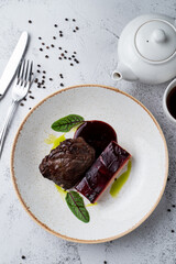 Slow cooked, stewed beef cheeks, directly above view on white stone table, with knife and fork around