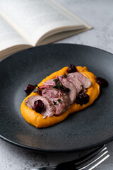 Close up of sliced duck fillet with pumpkin puree on dark dish, bright, beautiful photo for a magazine or restaurant menu