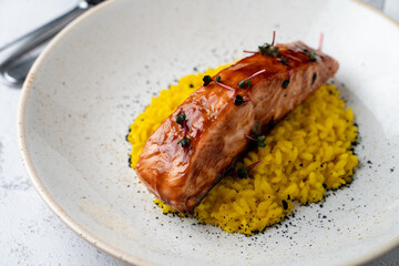 Salmon fillet grilled in teriyaki sauce with spicy rice on a wide plate