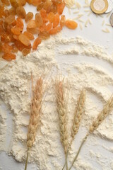 Flour, wheat, rice, raisins and coins on a white background
