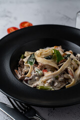 Beef pasta with creamy sauce in a black bowl