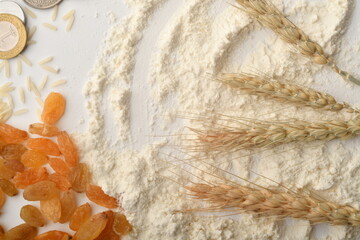 Flour, wheat, rice, raisins and coins on a white background