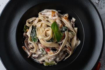 Beef pasta with alfredo sauce, vegetables and fresh basil, close up, appetizing shot