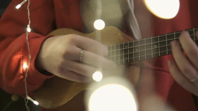 Hands of young pretty girl playing on brown ukulele 4K