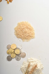 Flour, wheat, rice, raisins and coins on a white background