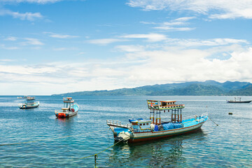 Fototapeta premium Traditional wooden boats with the fisherman in the Beautiful Amahusu Beach in Ambon, Maluku, Indonesia.