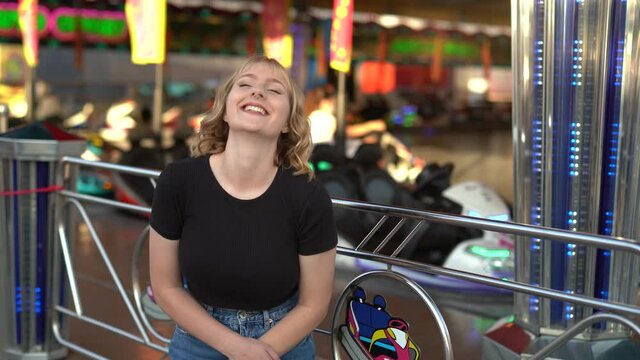 Chica rubia espa&ntilde;ola sonriendo y posando en zona de atracciones de una feria