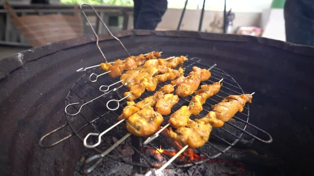 Carne variada sobre barbacoa en el exterior con amigos de fondo