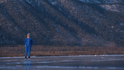 The girl train on ice speed skating. The child skates in the winter in blue sportswear suit, sport...