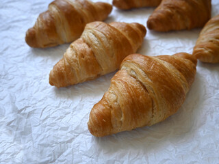 Closeup of delicious homemade golden croissants on baking paper background