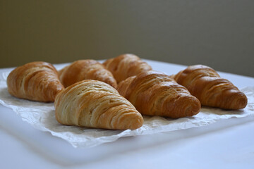 Closeup of delicious homemade golden croissants on baking paper and dark background