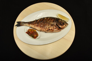 Roasted fish with lemon slices and  spicy sauce,dorada