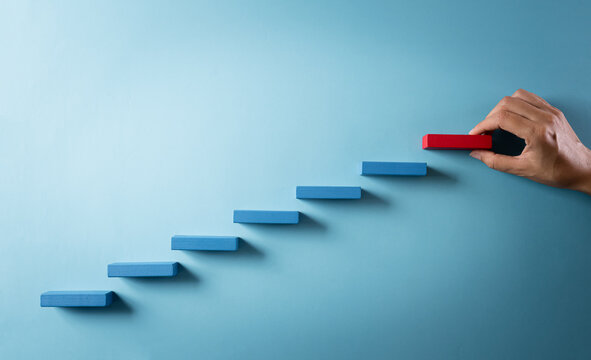 Concept Of Building Success Foundation. Hand Holding Wooden Block Stacking As Step Stair, Success In Business Growth Concept On Pastel Background.