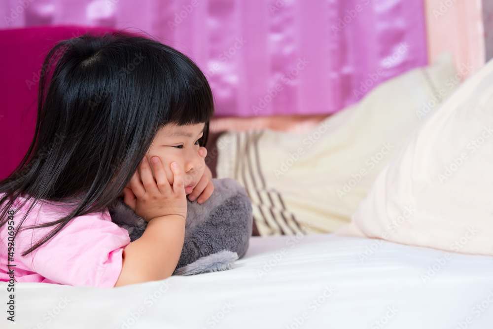 Wall mural cute 4 year old asian girl lying prone on the mattress. little kid holding her chin. touchy child, b